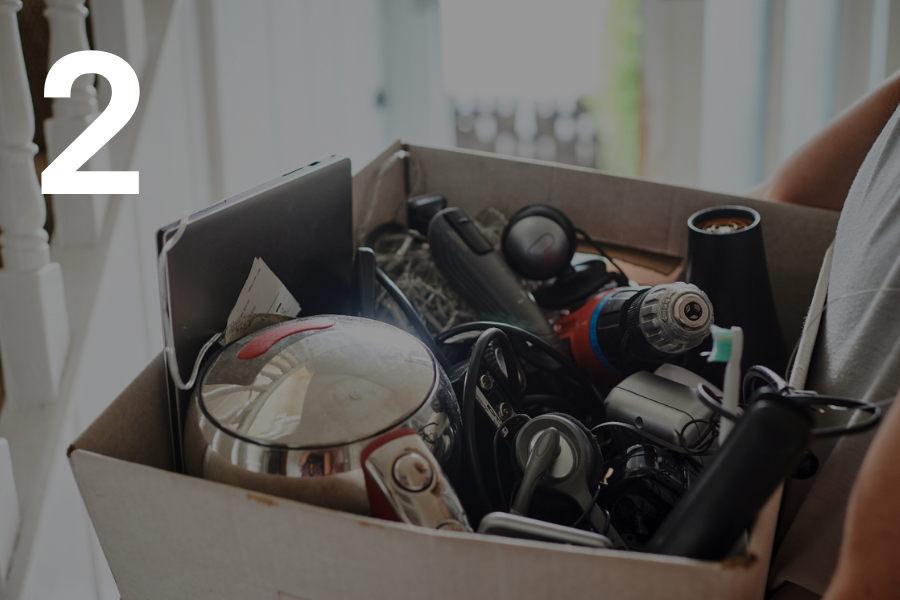 2. Person carrying box of electrical items ready for recycling.