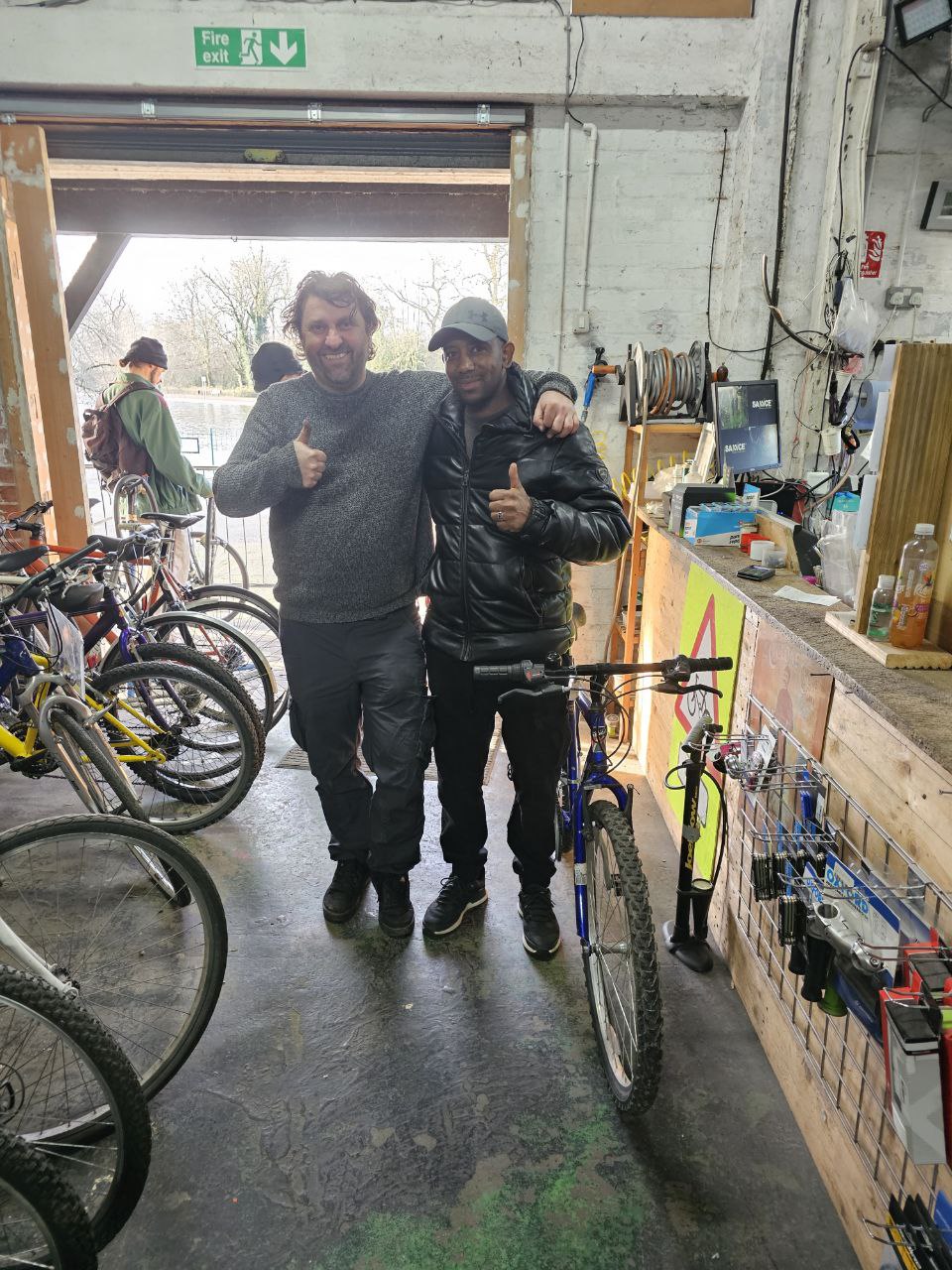 Bike mechanic stands with a refugee who has received a bike