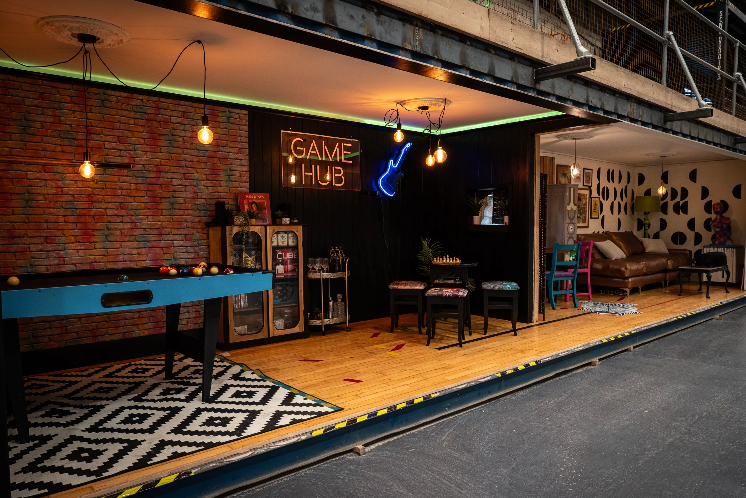 an area set up to look like a games room, with pool table, furniturem and neon sign