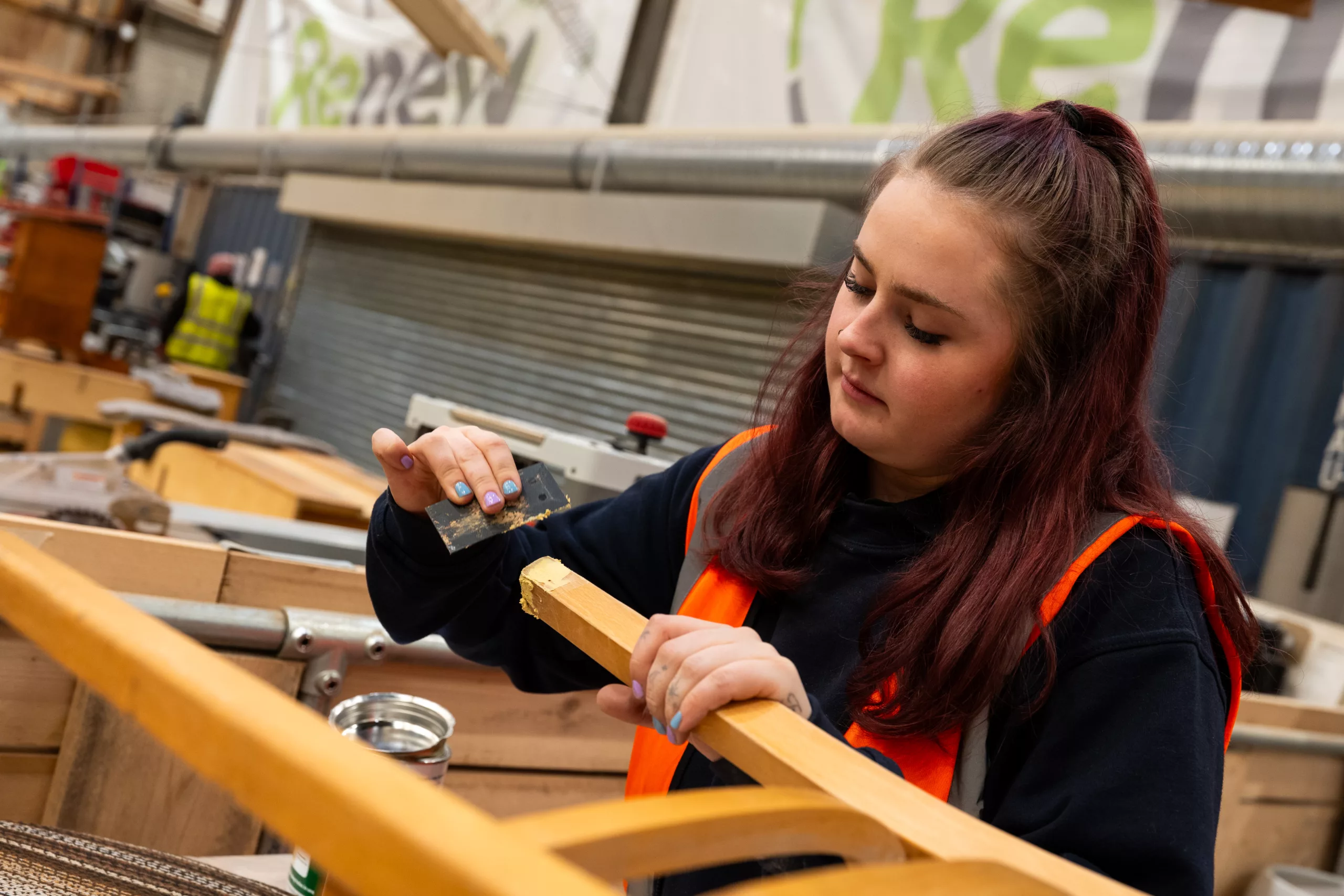 person sanding down a piece of furniture at the Renew Hub