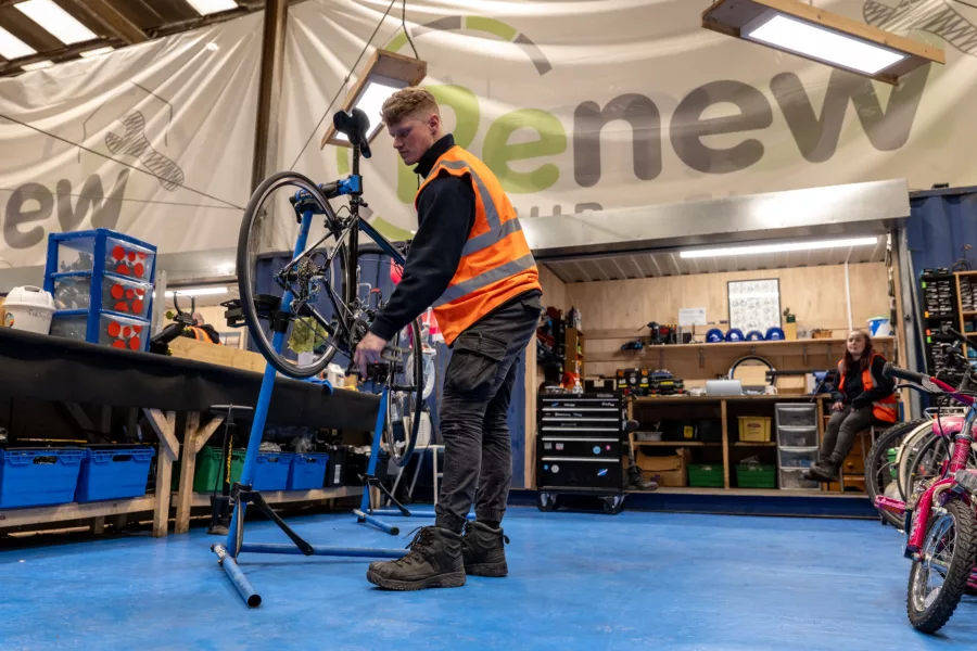 person wearing high-vis jacket fixing a bike in a workshop