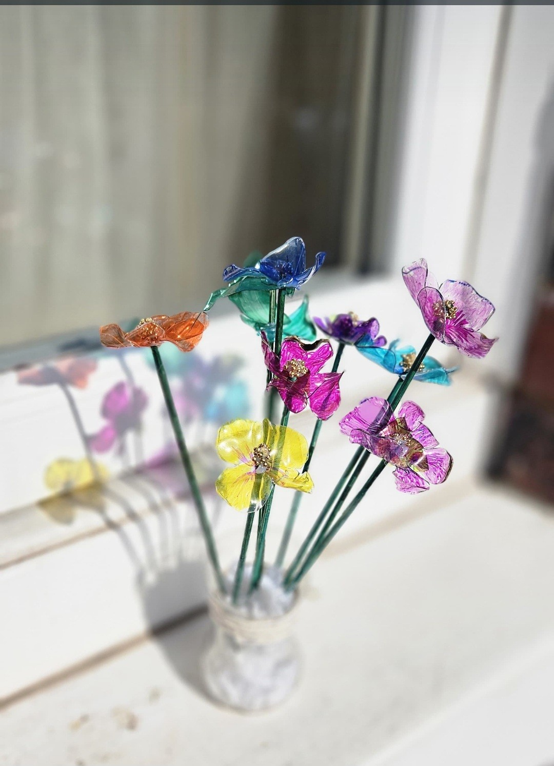 I made flowers and a vase using recycled plastic bottles, old wooden skewers and some beads and string. I used heat on the plastic flowers to make them look more 3D and coloured the flowers with marker pens.