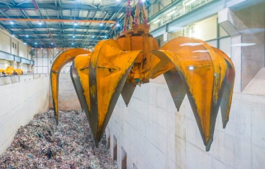 Large mechanical claw handing over piles of general waste at the Viridor 'Energy from Waste' facility in Runcorn.