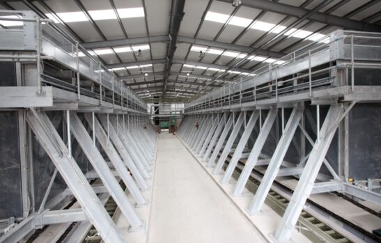 Wide angle shot of a composting facility. A number of large composting vessells with walkway down the middle. 