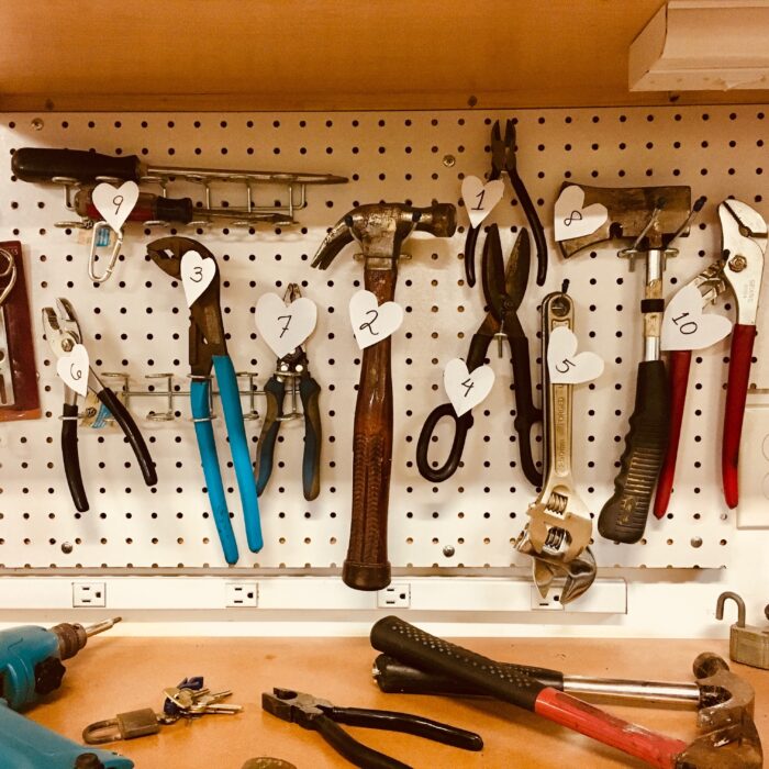 workshop tools hung on a metal wall, plyers, hammer, scissors, screwdrivers